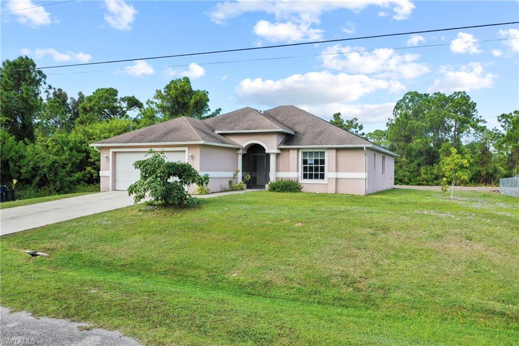 View of front of property featuring stucco siding, a front yard, concrete driveway, and an attached garage