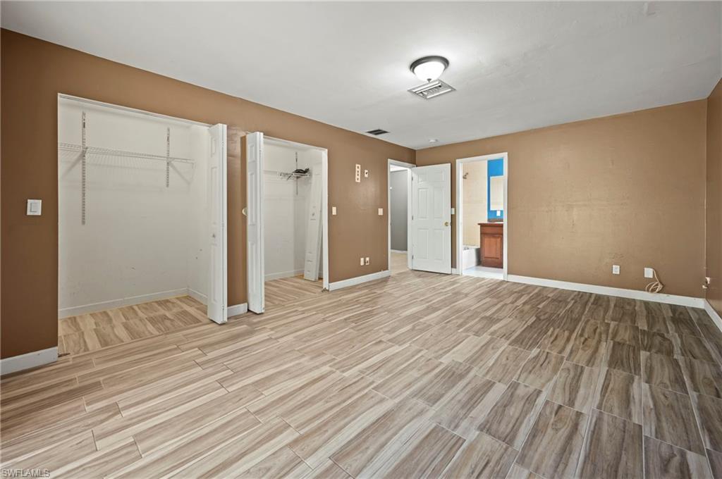 Unfurnished bedroom featuring two closets, wood tiled floors, and ensuite bathroom