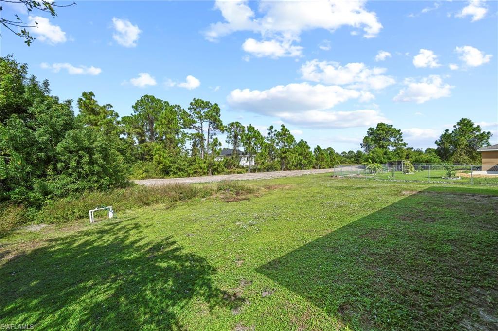 View of grassy yard with view of wooded area