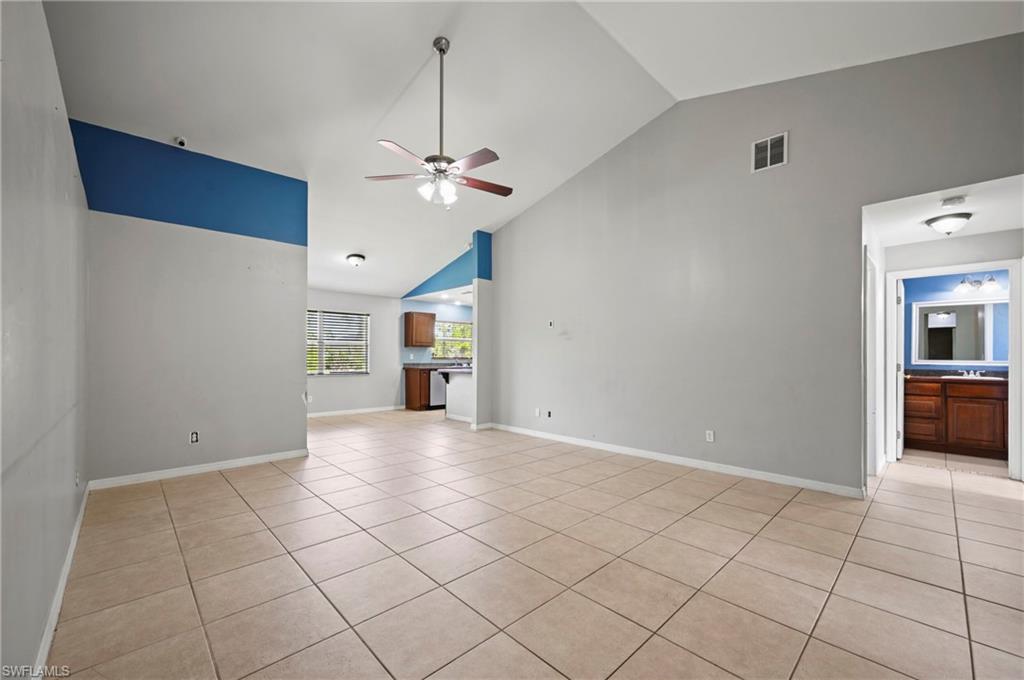 Unfurnished living room featuring light tile patterned floors, high vaulted ceiling, and a ceiling fan