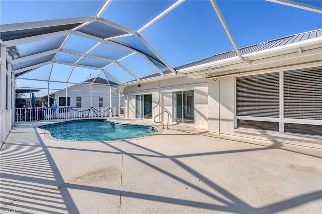 Outdoor pool featuring a sunroom, a patio, and glass enclosure