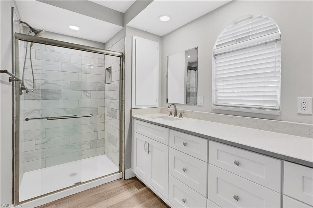 Bathroom with vanity, a shower stall, and light wood-style floors