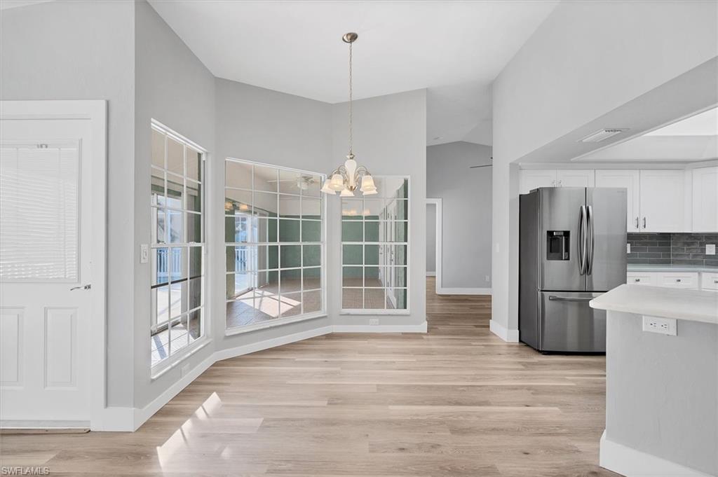 Unfurnished dining area with a chandelier, light wood-type flooring, and lofted ceiling