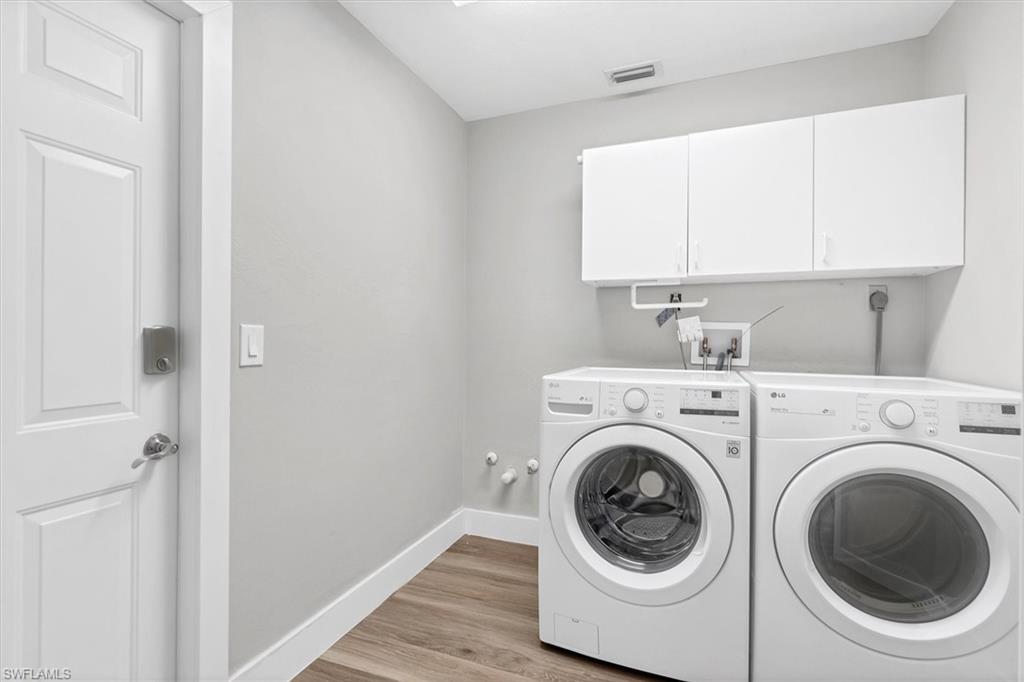 Washroom with cabinet space, light wood-style floors, and washing machine and clothes dryer