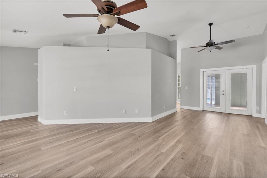 Unfurnished living room with french doors, light wood-style floors, ceiling fan, and high vaulted ceiling