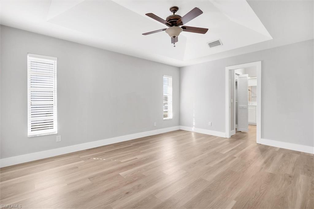 Spare room featuring a raised ceiling, light wood-type flooring, and a ceiling fan