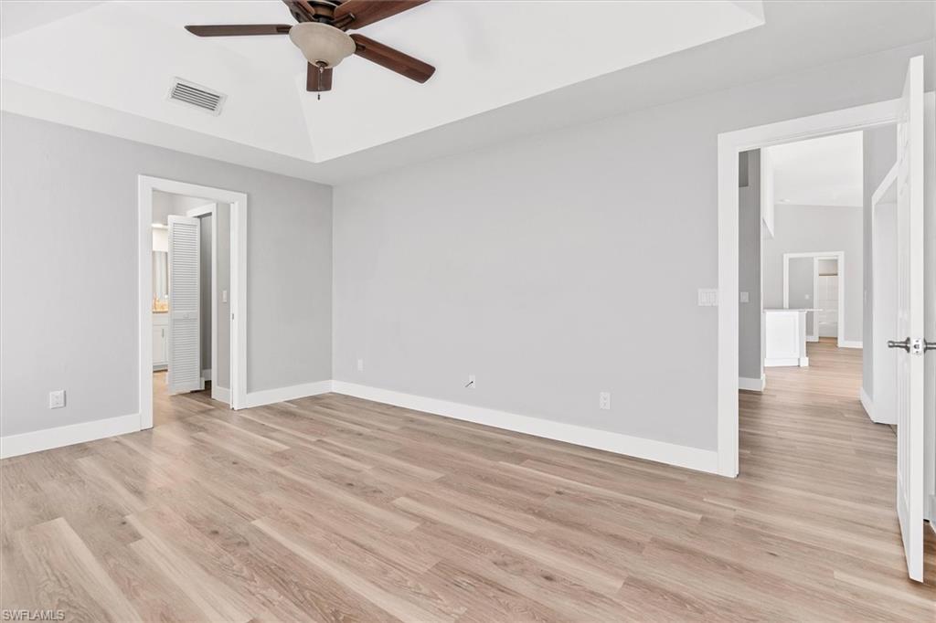 Unfurnished bedroom featuring light wood finished floors, ceiling fan, and ensuite bath