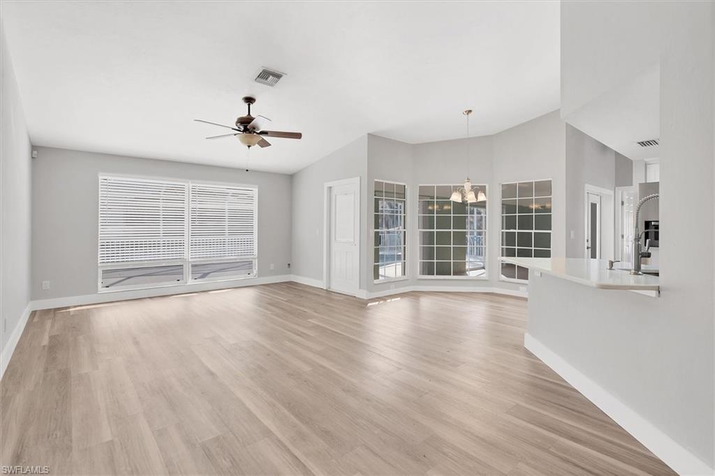 Unfurnished living room with a chandelier, light wood finished floors, vaulted ceiling, and ceiling fan