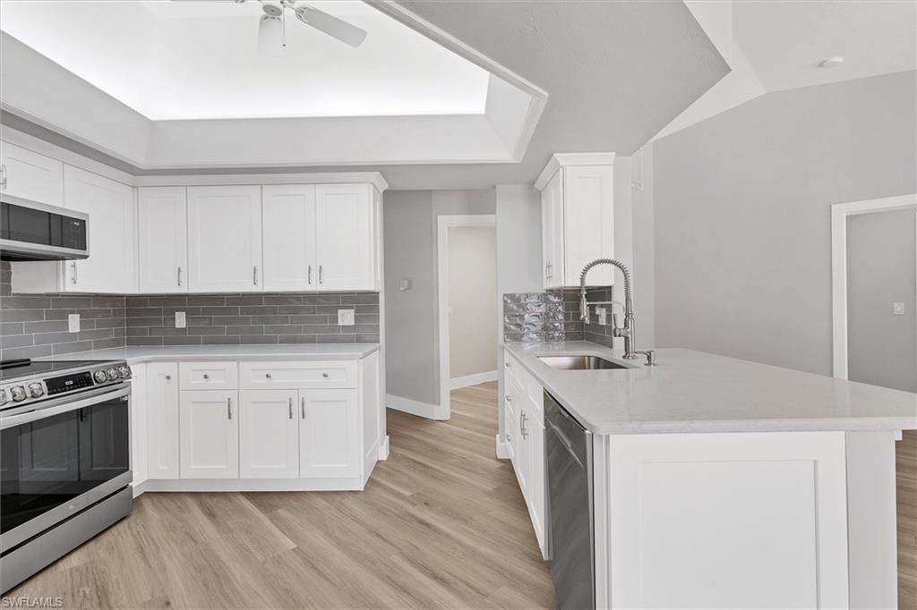 Kitchen featuring stainless steel appliances, light stone counters, decorative backsplash, and light wood-type flooring