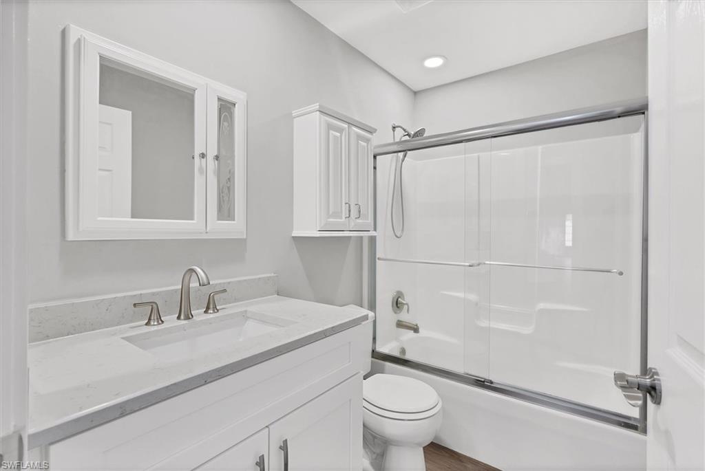 Bathroom with combined bath / shower with glass door and vanity