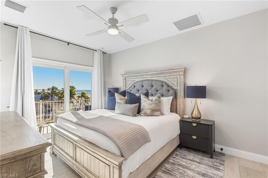 Bedroom featuring light wood finished floors, ceiling fan, access to exterior, and a water view