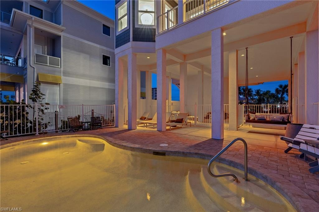 Pool at dusk featuring an outdoor pool, a patio area, and a balcony