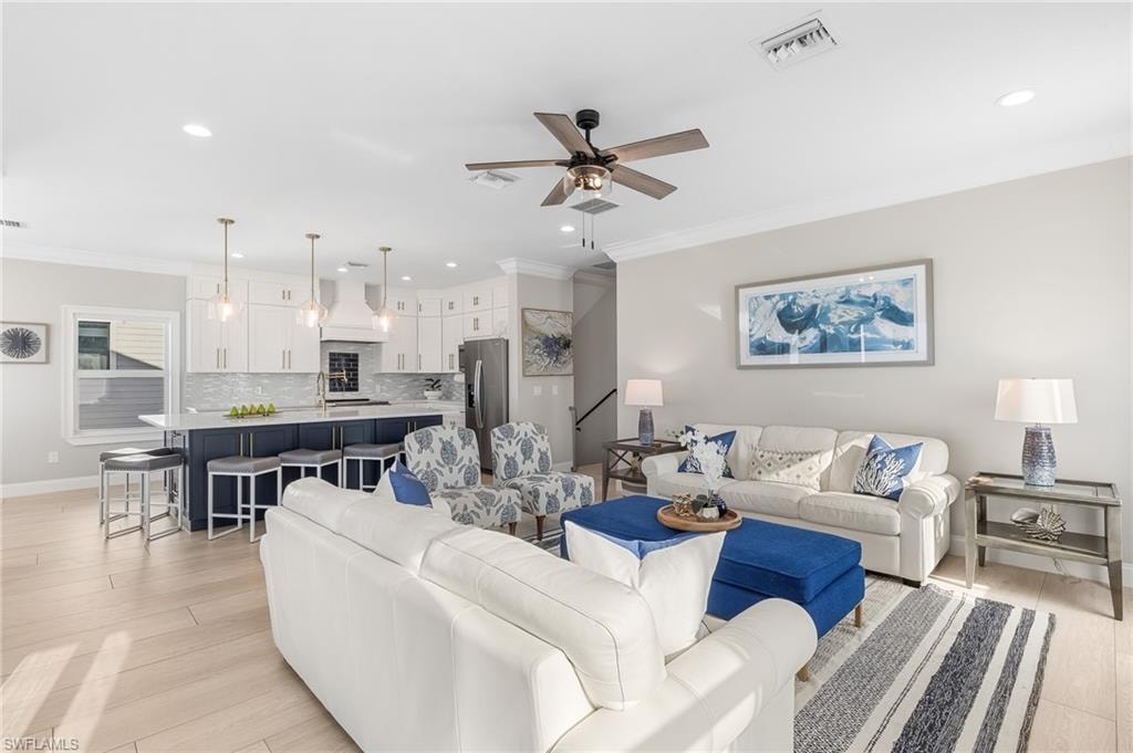 Living room with ornamental molding, light wood finished floors, a ceiling fan, and recessed lighting
