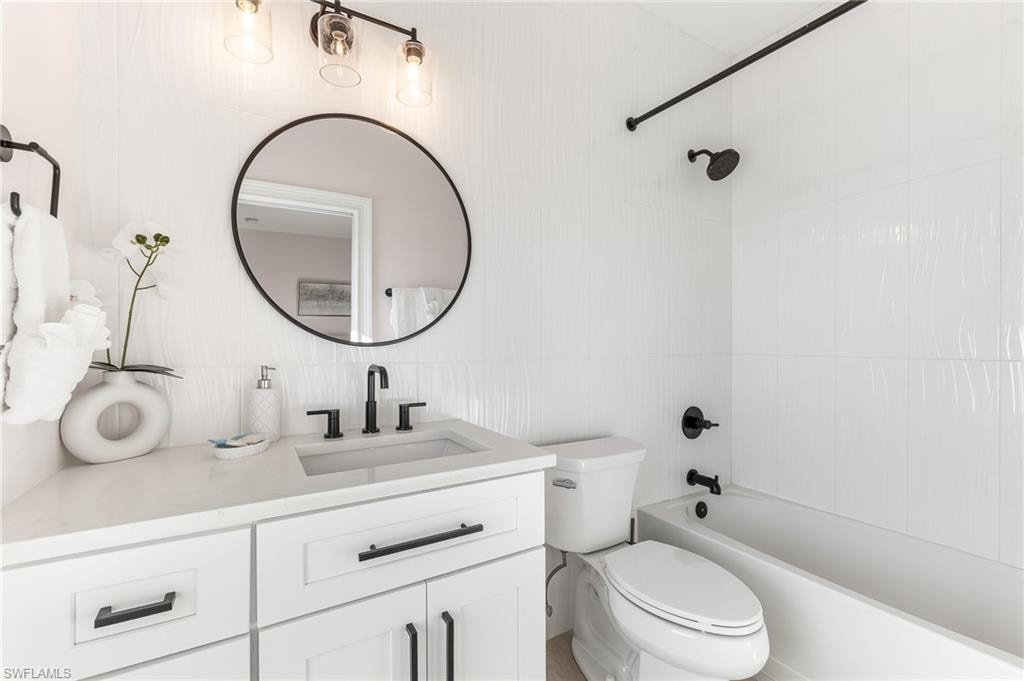 Full bath with vanity, shower / tub combination, and tile walls