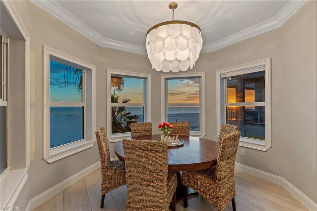 Dining area featuring crown molding, a water view, light wood-style flooring, and a chandelier
