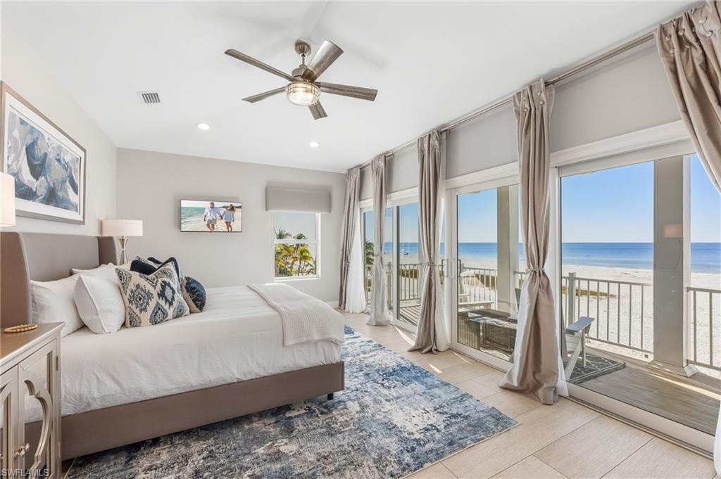Bedroom with access to exterior, view of water and beach, ceiling fan, and recessed lighting