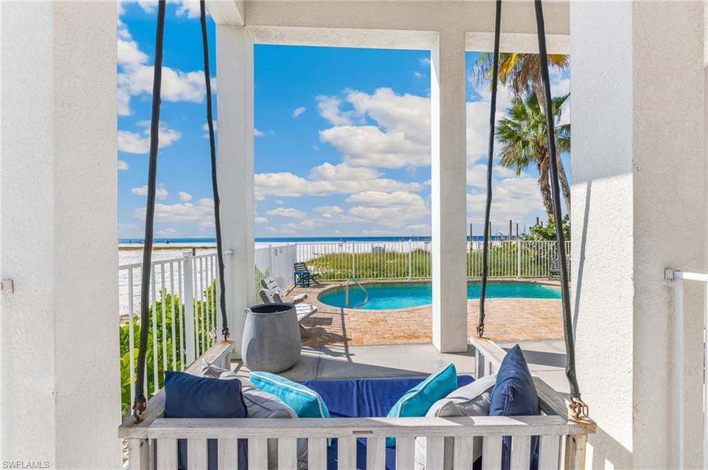 Balcony featuring view of water and beach and view of pool area