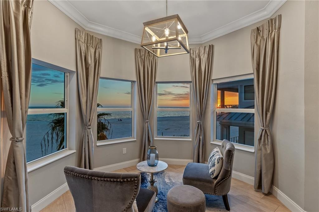Living area featuring crown molding, light wood-type flooring, a water view, and a chandelier