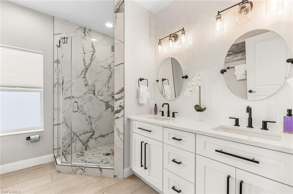 Bathroom featuring double vanity and a marble finish shower