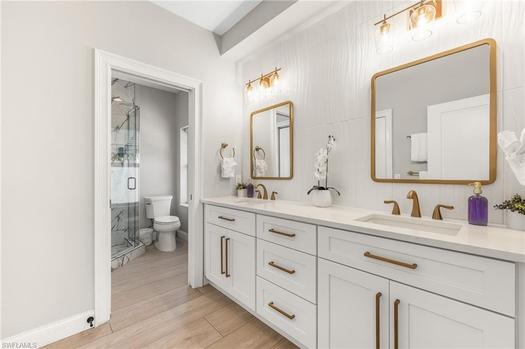 Bathroom with double vanity, a shower stall, and light wood-style floors