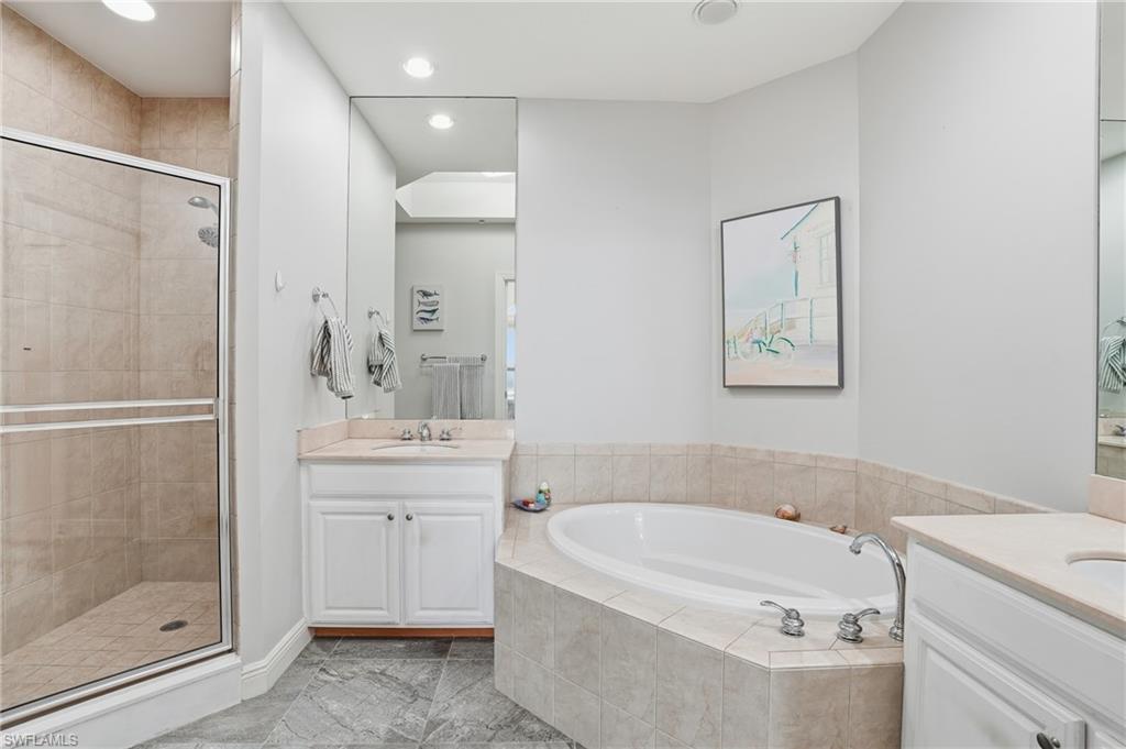 Bathroom with a shower stall, two vanities, a garden tub, and recessed lighting - Virtually Edited Image