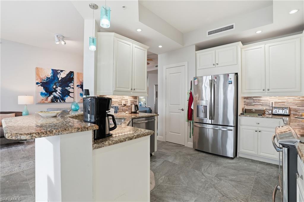 Kitchen with light stone countertops, tasteful backsplash, stainless steel appliances, white cabinetry, and recessed lighting - Virtually Edited Image