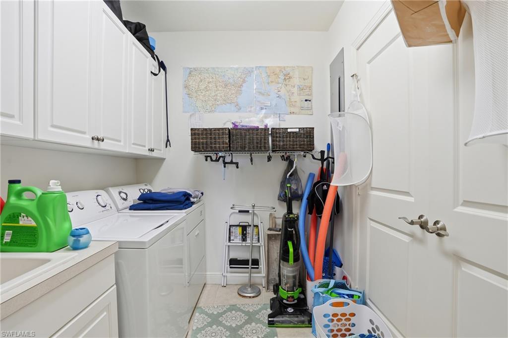 Laundry area featuring cabinet space, light tile patterned flooring, and separate washer and dryer - Virtually Edited Image