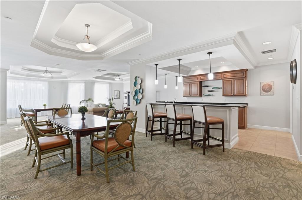 Community room featuring a raised ceiling, ornamental molding, light colored carpet, and light tile patterned floors - Virtually Edited Image