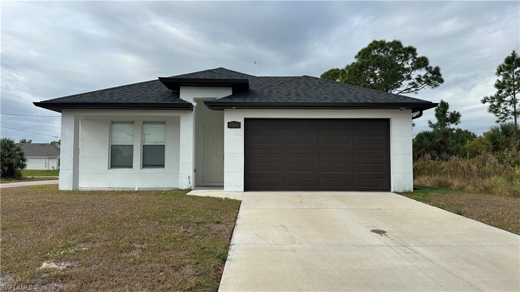 View of front of property with roof with shingles, driveway, a garage, and a front lawn