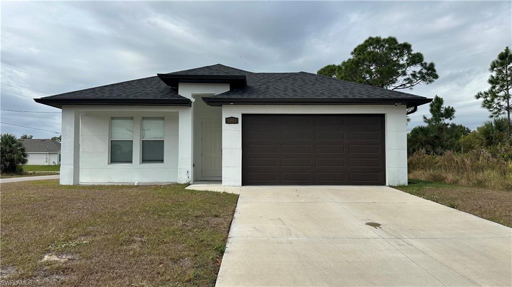 View of front of home featuring a shingled roof, driveway, a garage, a front lawn, and stucco siding