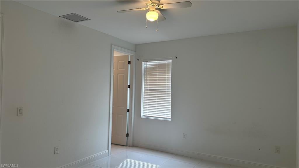 Empty room featuring a ceiling fan and light tile patterned floors