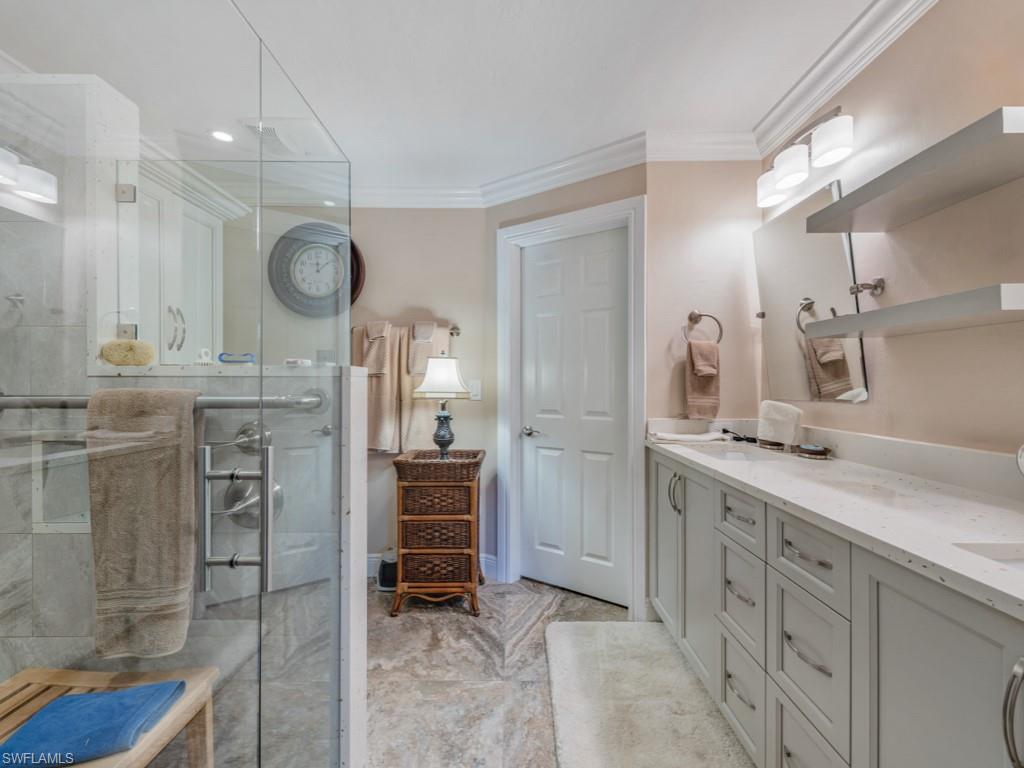 Bathroom featuring double vanity, a shower stall, ornamental molding, and recessed lighting
