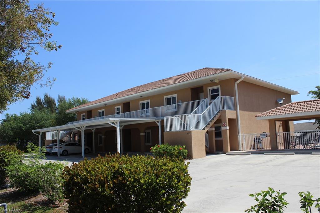 Back of property with stairway, stucco siding, concrete driveway, and a tile roof