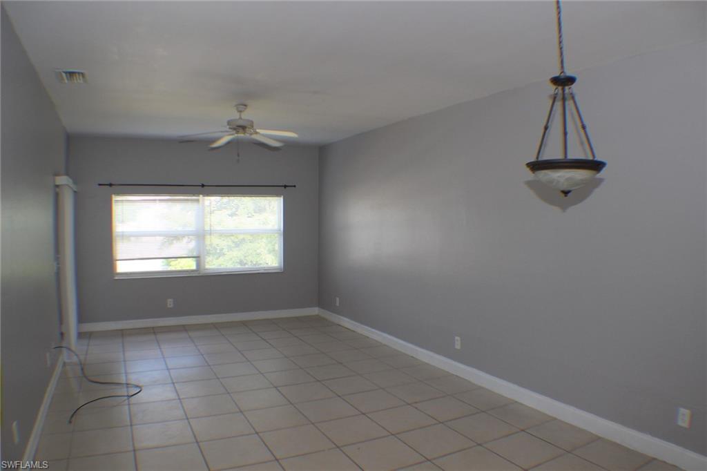 Empty room with light tile patterned floors and ceiling fan