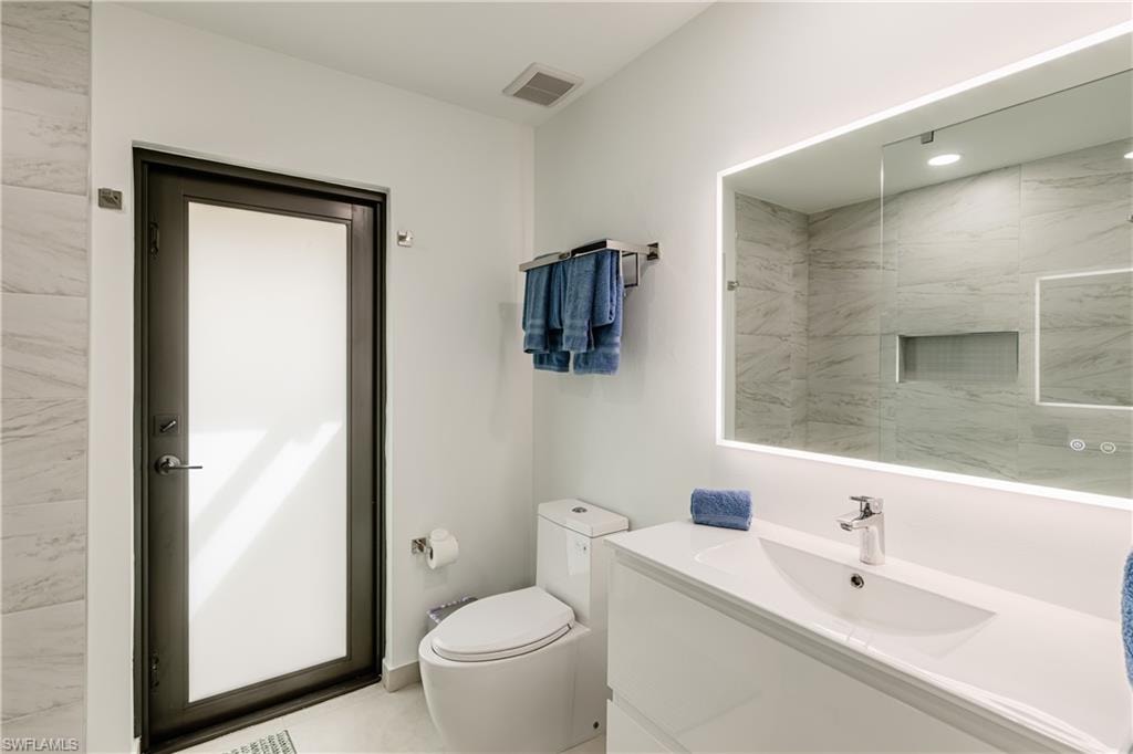 Bathroom featuring modern mirror, vanity, toilet and shower with access to outdoor area