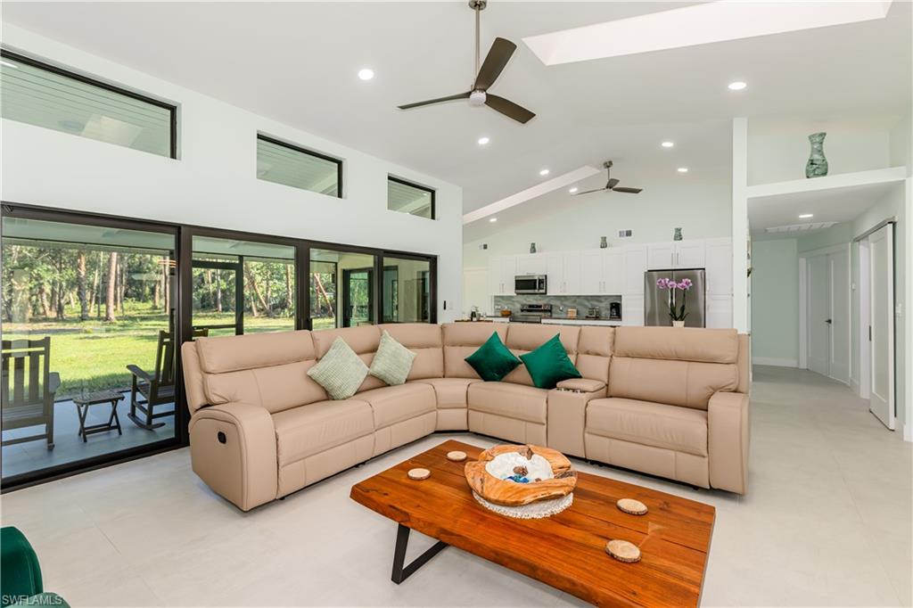 Living room with high vaulted ceiling, recessed lighting, a ceiling fan, and a skylight