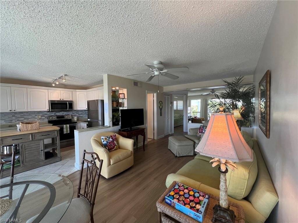 Living room featuring wood finished floors, a textured ceiling, a ceiling fan, and rail lighting