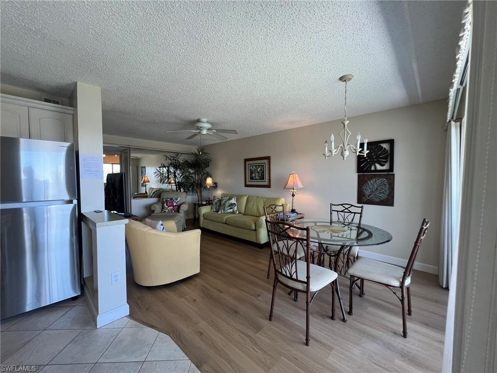 Dining area featuring ceiling fan, light wood-type flooring, a textured ceiling, and a chandelier