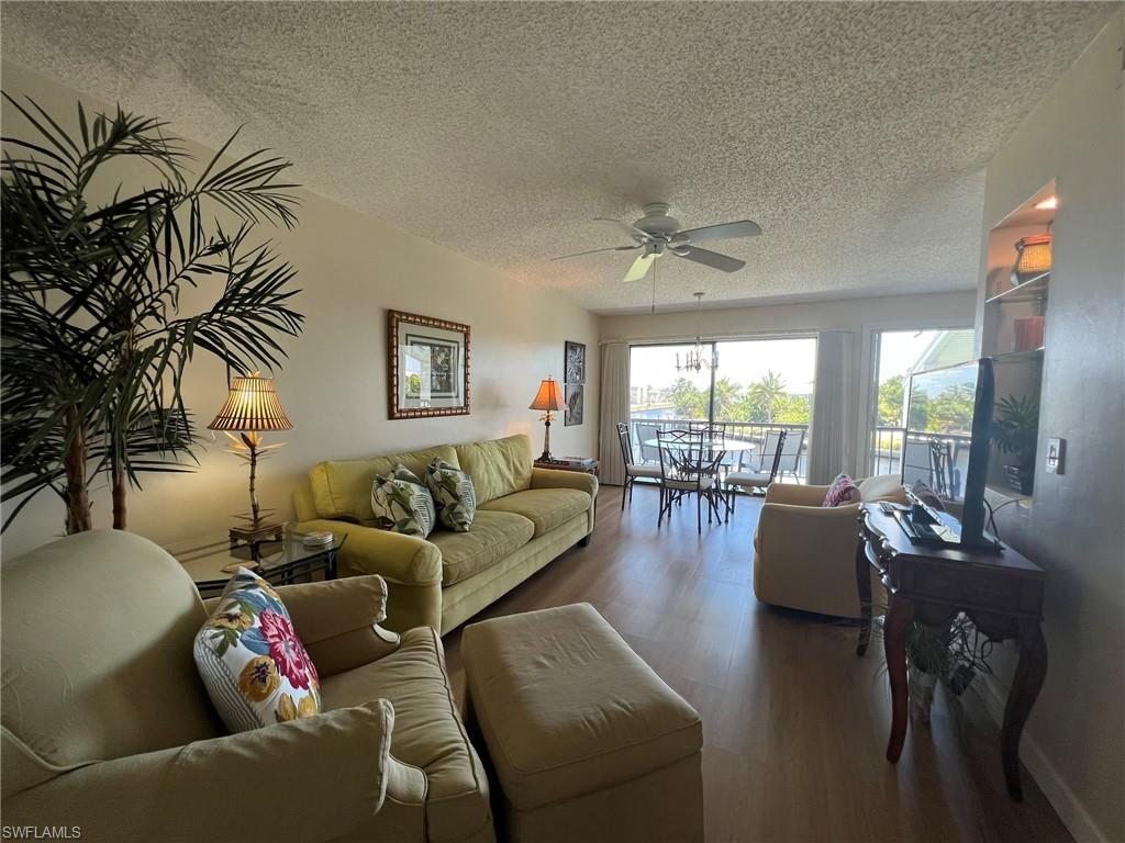 Living area featuring wood finished floors, a textured ceiling, and ceiling fan