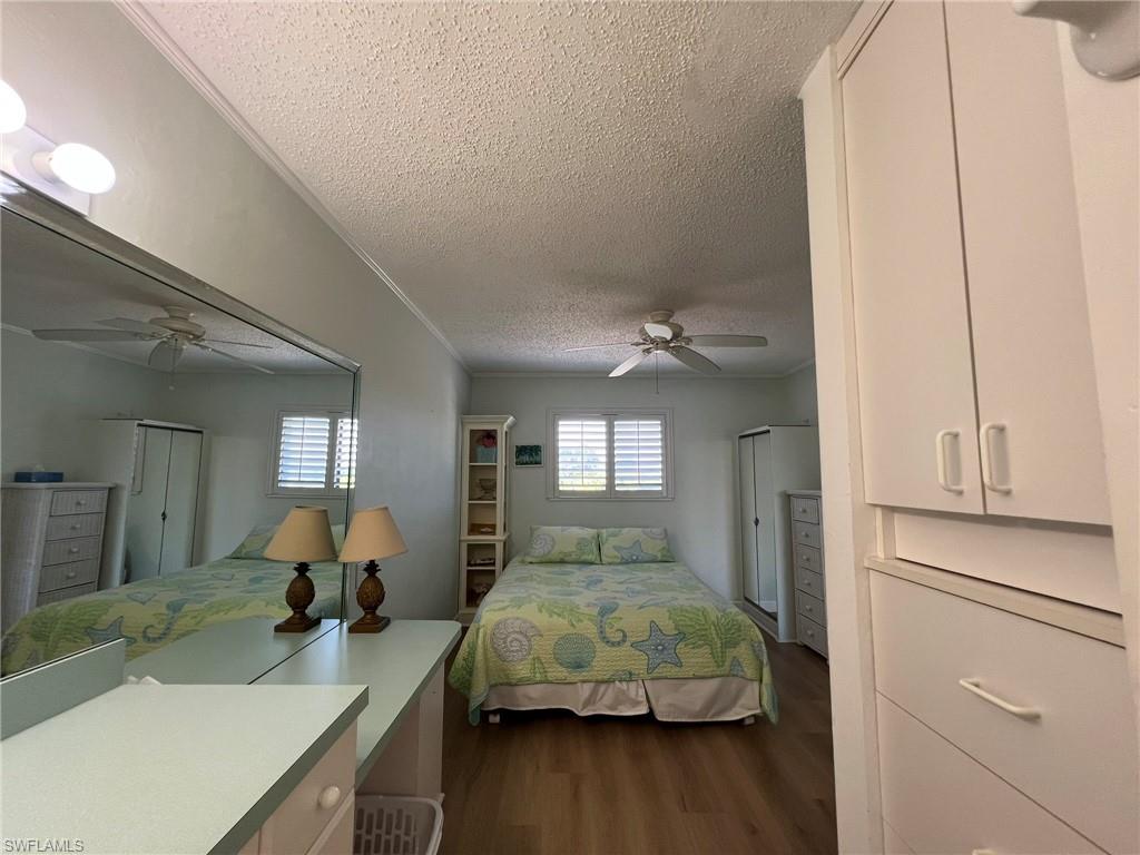 Bedroom featuring crown molding, a textured ceiling, dark wood finished floors, and ceiling fan