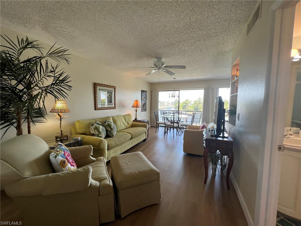 Living room with wood finished floors, a textured ceiling, and a ceiling fan