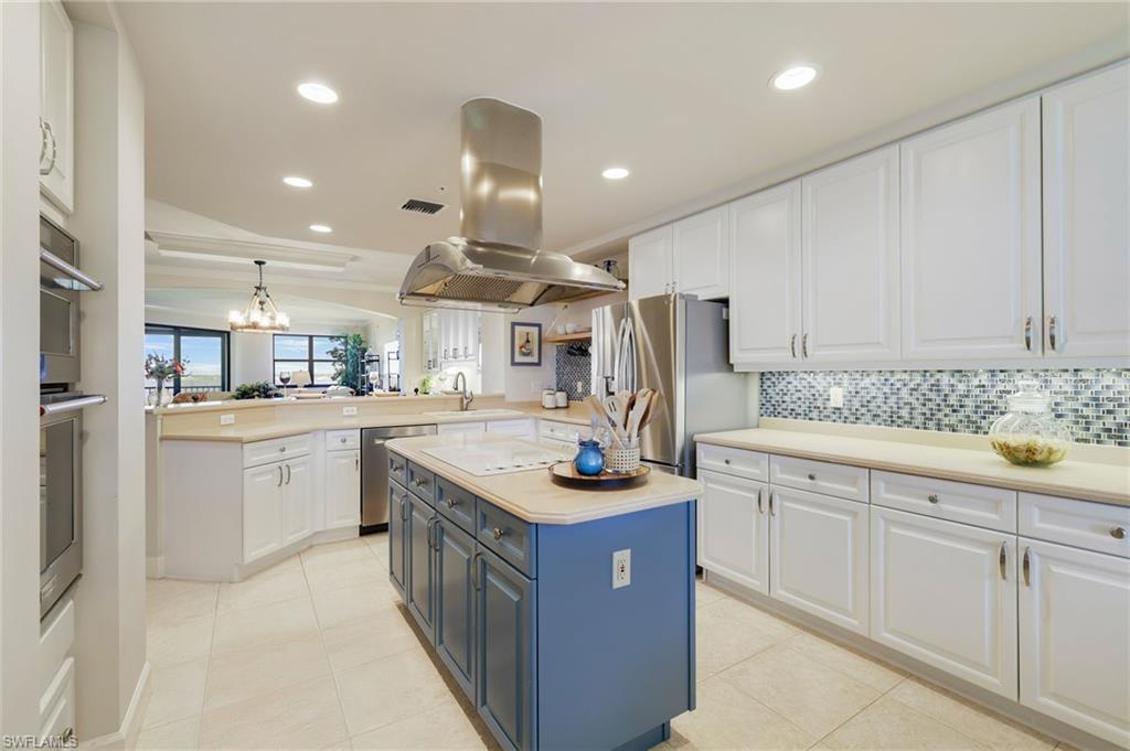 Kitchen featuring 42" white cabinetry, open shelves, stainless steel appliances, center island and pantry