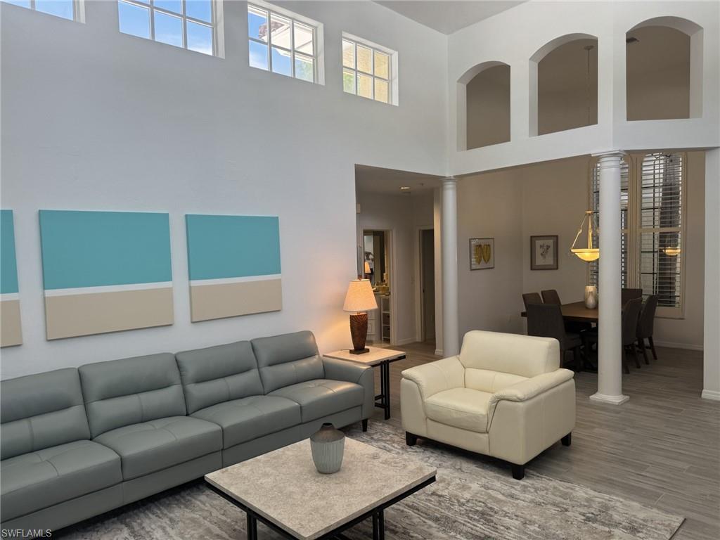 Living area with wood finished floors, a high ceiling, and ornate columns