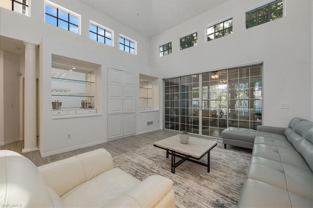 Living area with wood finished floors, a towering ceiling, and healthy amount of natural light