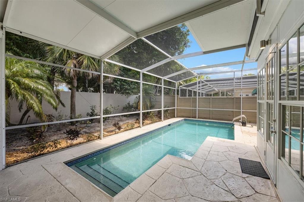 View of pool featuring a sunroom, glass enclosure, a patio area, and a fenced backyard
