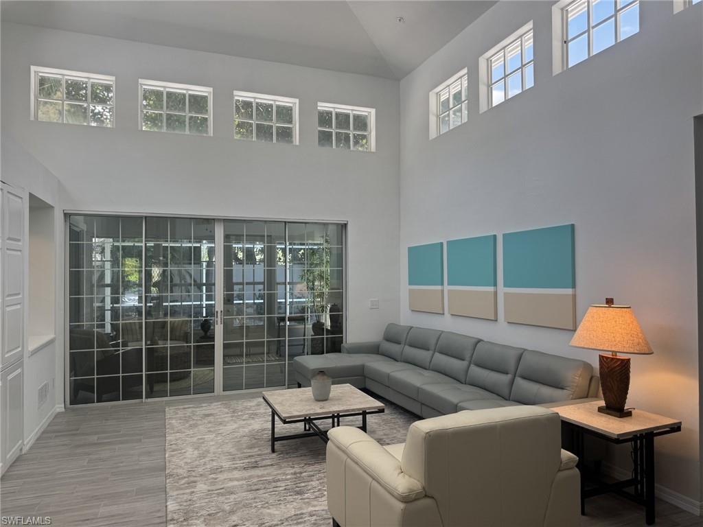 Living room featuring healthy amount of natural light, high vaulted ceiling, and wood finished floors