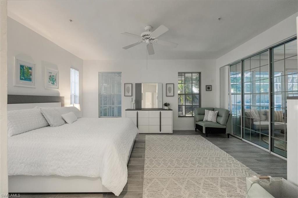 Bedroom with a ceiling fan, multiple windows, and wood finished floors
