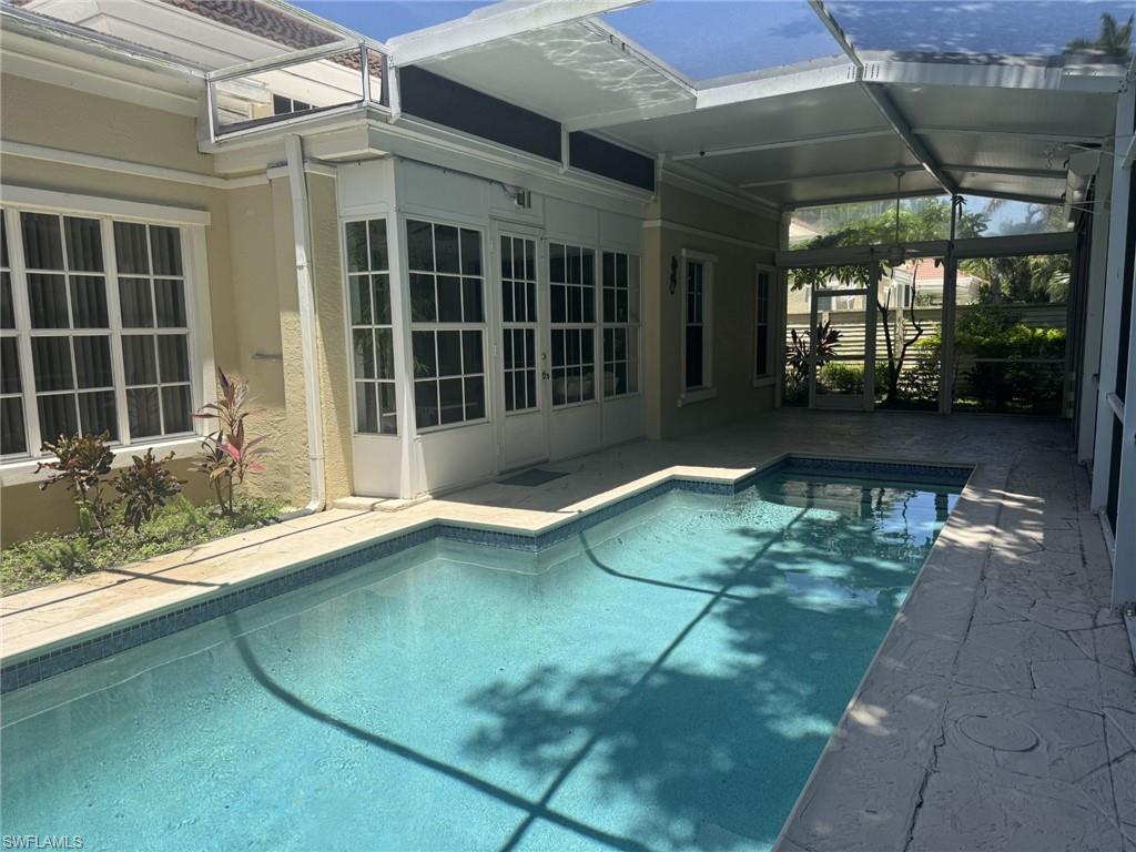 Outdoor pool featuring a patio, a sunroom, and glass enclosure