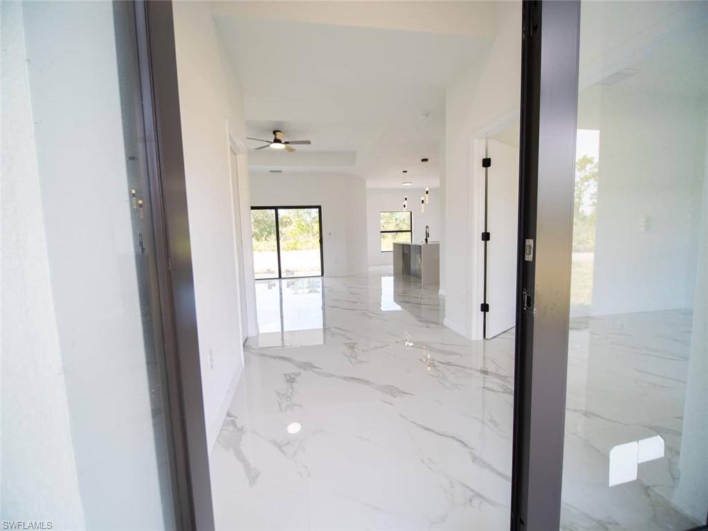 Corridor featuring light marble finish floors and baseboards