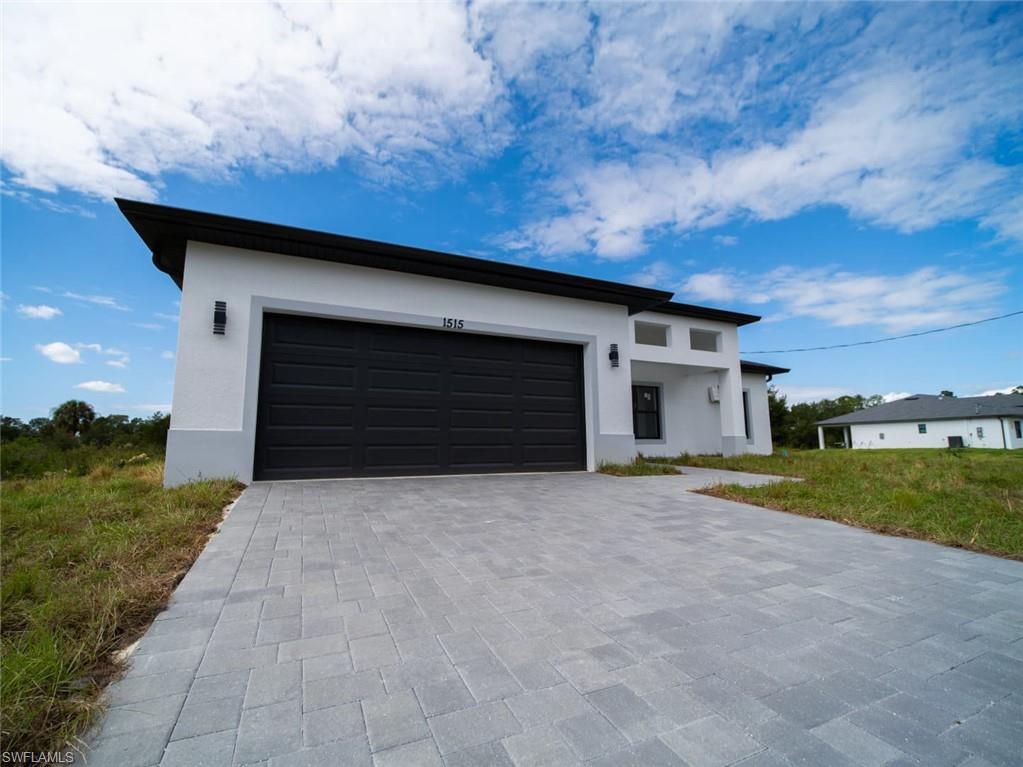 View of front of home with stucco siding, decorative driveway, and an attached garage